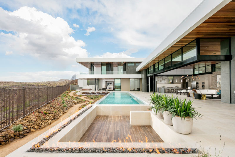 This modern house opens up to a large outdoor entertaining area and swimming pool, while a sunken area perfect for a few couches is surrounded by an outdoor fireplace.