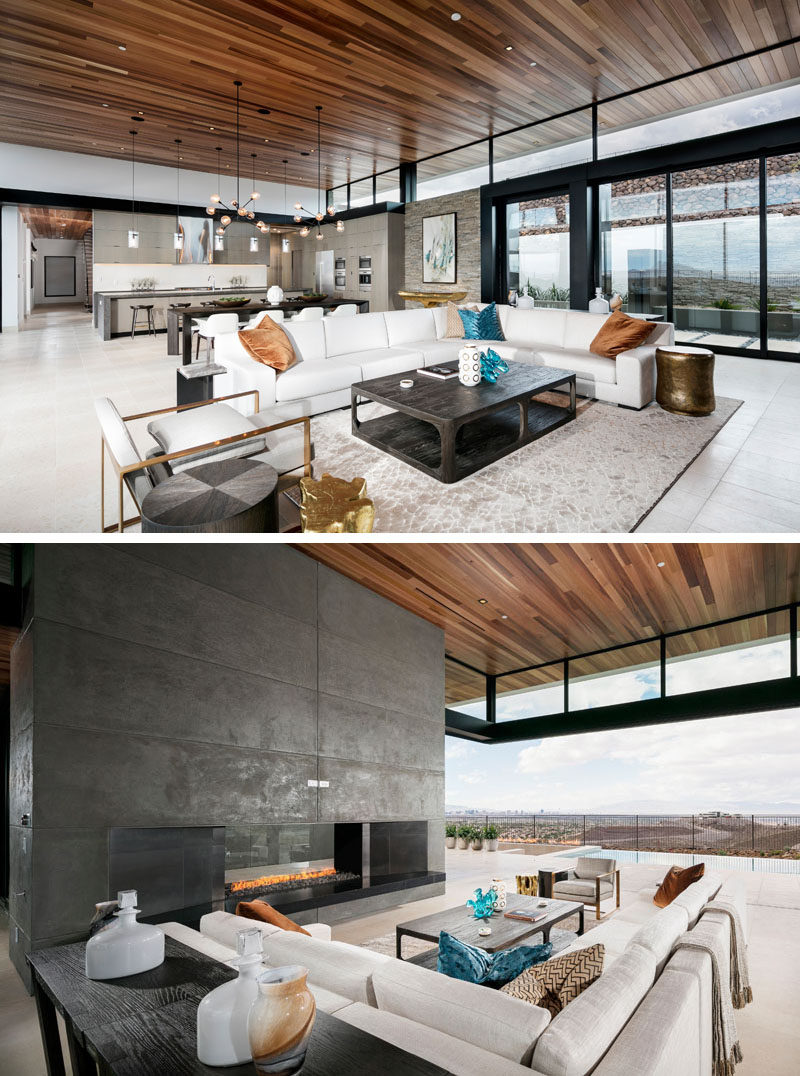 This modern house completely opens up to the view. High ceilings covered in wood draw your eye upward and make the room feel grand and spacious. The living room, dining and kitchen all share the same space, with the living room focused on a large fireplace.