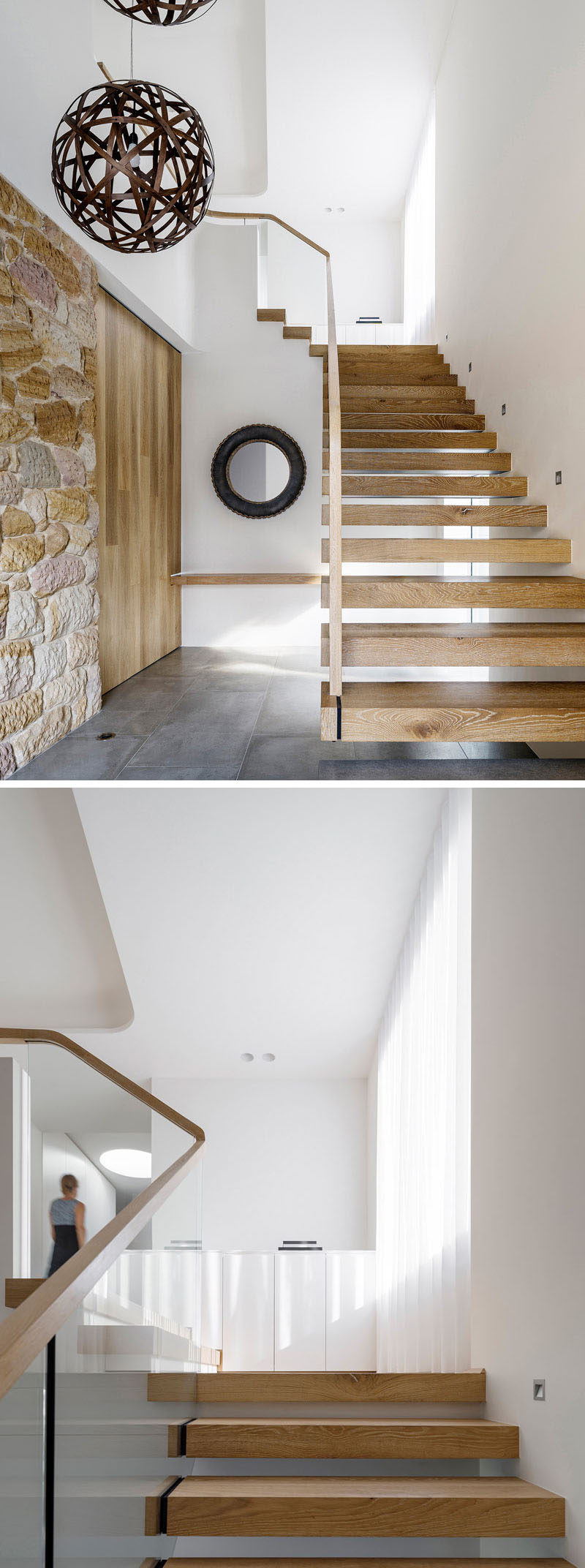 To the left of these modern wood and glass stairs is a recycled sandstone wall and large sliding wood door.