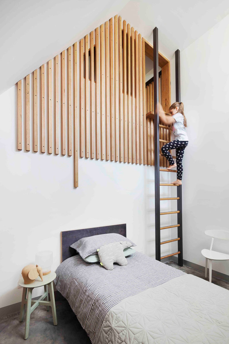 This modern kids bedroom has a loft area is reached via a ladder, with the loft partially hidden by wood slats.