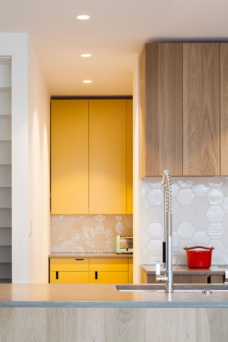 Behind this modern wood kitchen, is a hidden pantry room and secondary kitchen with yellow cabinets, that has the ovens and plenty of additional storage space.