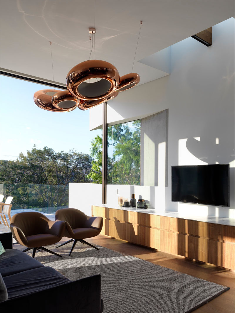 This small and modern living area features sculptural copper pendant lights and a light wood cabinet.