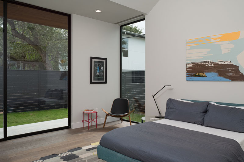 This master bedroom looks out onto the garden, and is filled with natural light from the floor-to-ceiling windows and vaulted ceiling.