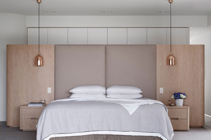 Symmetry was key in the design of this master bedroom with an upholstered headboard and hanging pendant lamps has beside lights.