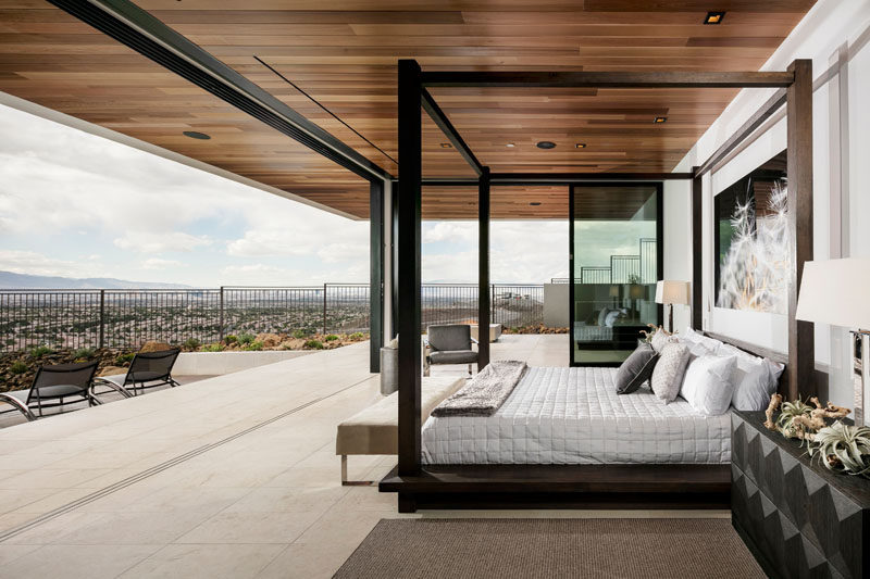 This modern master bedroom has a wood ceiling, uninterrupted views of the valley below and is completely open to the backyard and pool area.