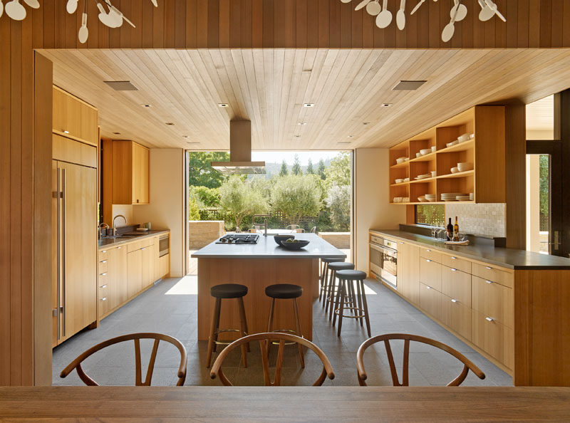 As part of this modern farmhouse renovation, the kitchen was opened up to the outdoors through large sliding pocket doors, and the original wood cabinets were replaced with modern cabinets and open shelving. Cedar siding was used to cover sections of the ceiling and walls throughout the renovated home.