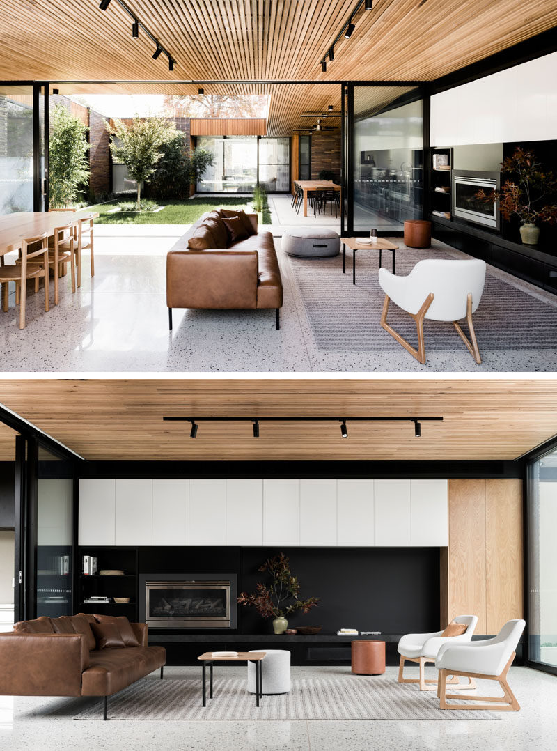 Inside this modern house, a timber batten ceiling contrasts the white concrete floor, keeping the interiors light and and airy. A black wall in the living helps to define the space in the large open room.