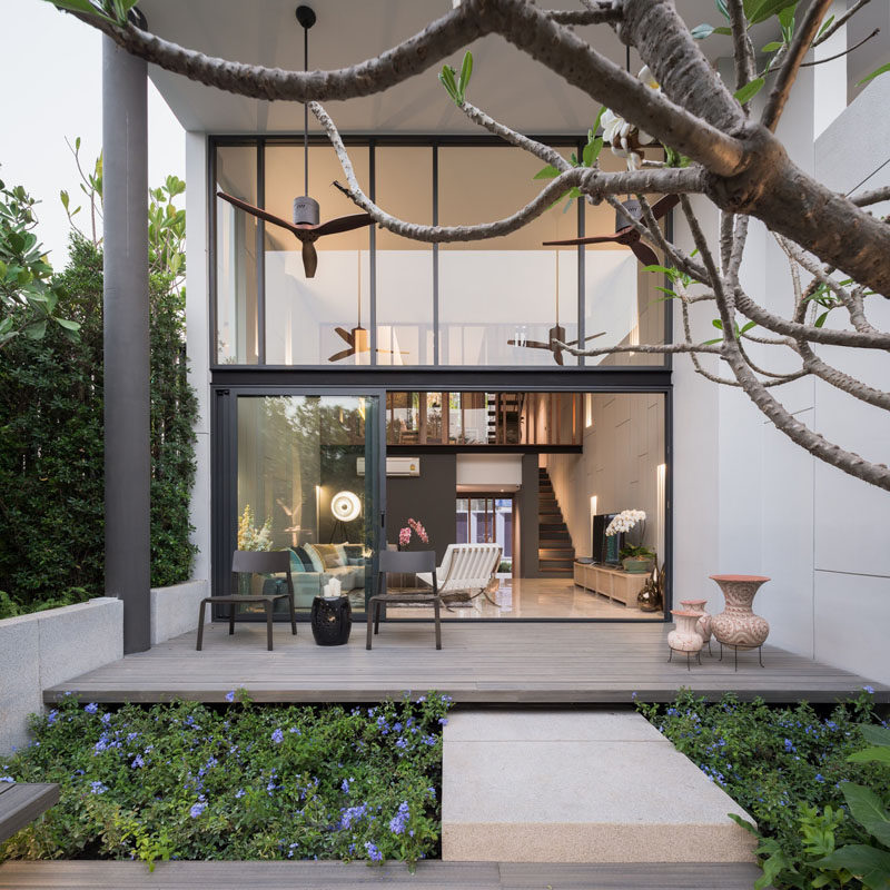 This modern house has a covered outdoor patio that looks out onto the backyard.