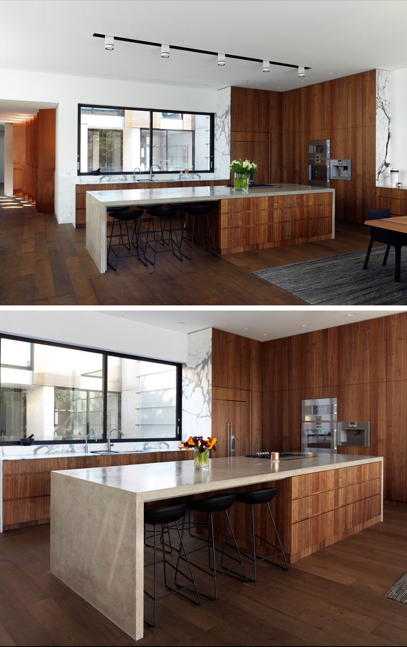 In this kitchen, dark wood cabinets have been combined with a light stone countertop to create a contemporary appearance. Large windows above the kitchen sink provide views of the courtyard.