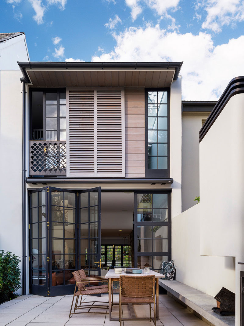 This modern row house has an internal courtyard at the rear of the home accessed through the main floor. A built-in bench provides seating for an outdoor dining table.