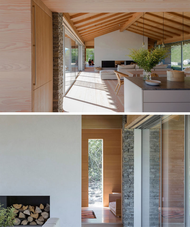 Inside this modern house, the gabled ceiling creates a sense of openness, and the simple neutral color palette makes the interior feel relaxed and inviting. The kitchen, dining and living room all share the main space, with the double-sided fireplace being the focal point in the living room.