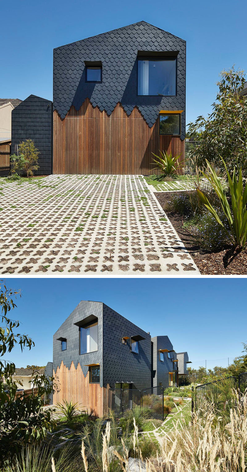 Covering the exterior of this modern house are dark grey slate tiles in a couple of different patterns, with some sections having a staggered finish to show the wood underneath, especially at the side of the home where the garage is located.