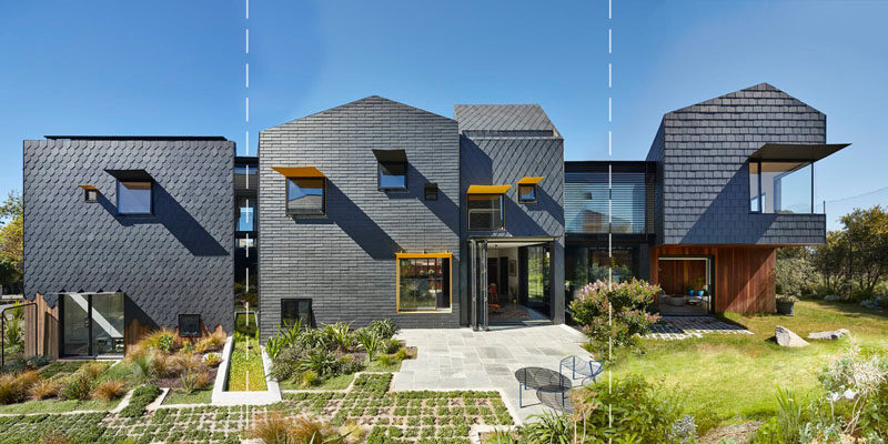 Covering the exterior of this modern house are dark grey slate tiles in a couple of different patterns, with some sections having a staggered finish to show the wood underneath, especially at the side of the home where the garage is located.