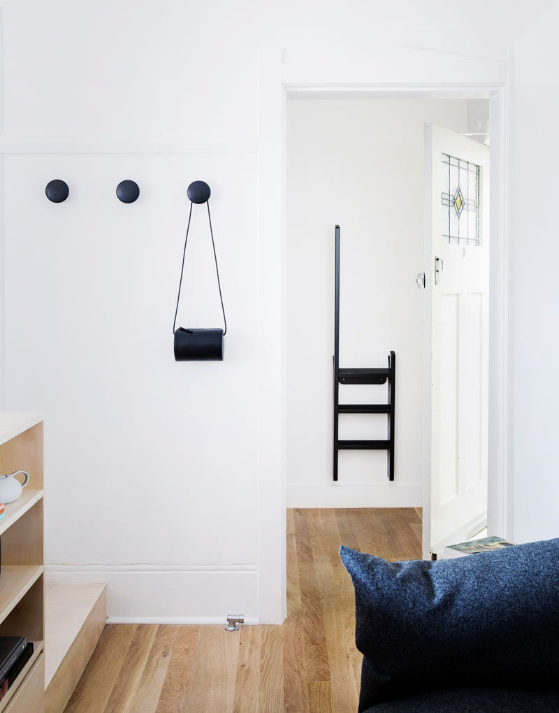 Simple round matte black hooks match the step ladder that hangs behind the front door in this small apartment.