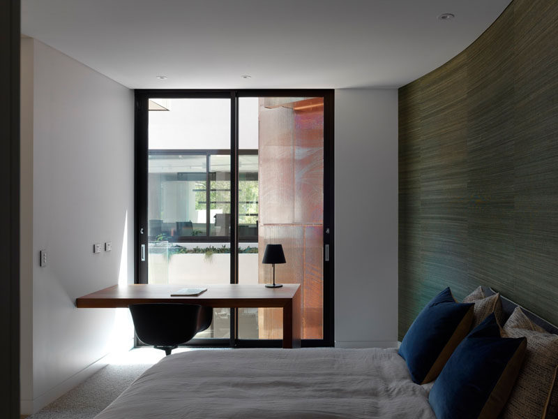 This small bedroom has a built-in desk and access to a small balcony that overlooks an internal courtyard.