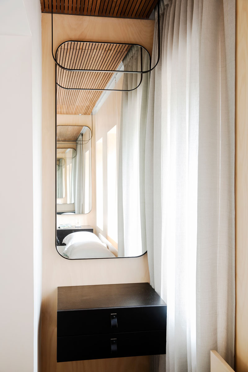 Beside each side of the bed in this small apartment, are floating black cabinets and curved mirrors, a throw-back to the art-deco era.