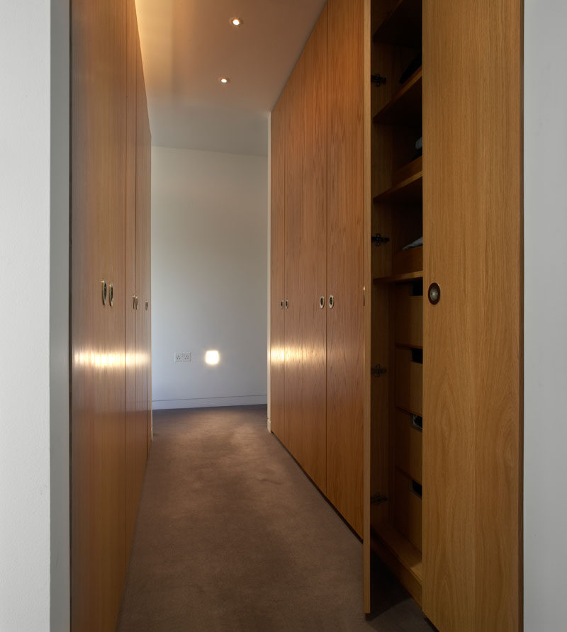 This modern walk-in closet has tall wood cabinets and plenty of storage.