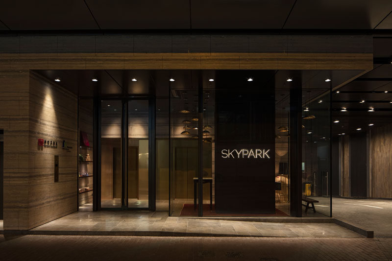 A dark lobby with minimal down lighting provides access to a bright and airy rooftop clubhouse and park.