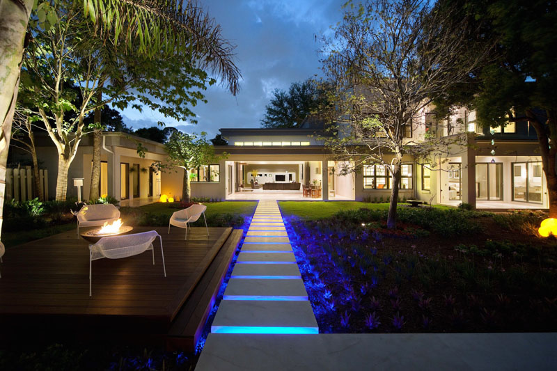 This modern path is lit by LED lights, leading from the patio to an entertaining space with seating and a firepit.