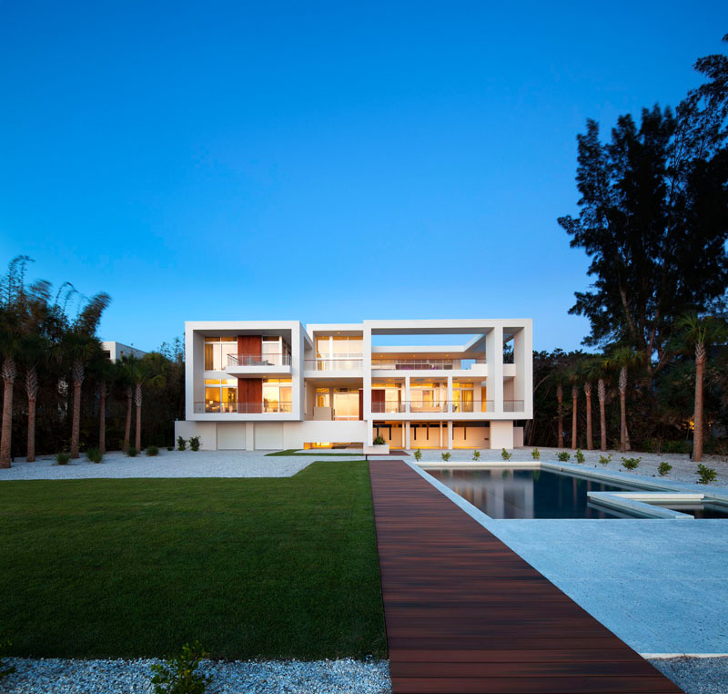 A modern dark wood walkway, divides the pool from grassy space at this home