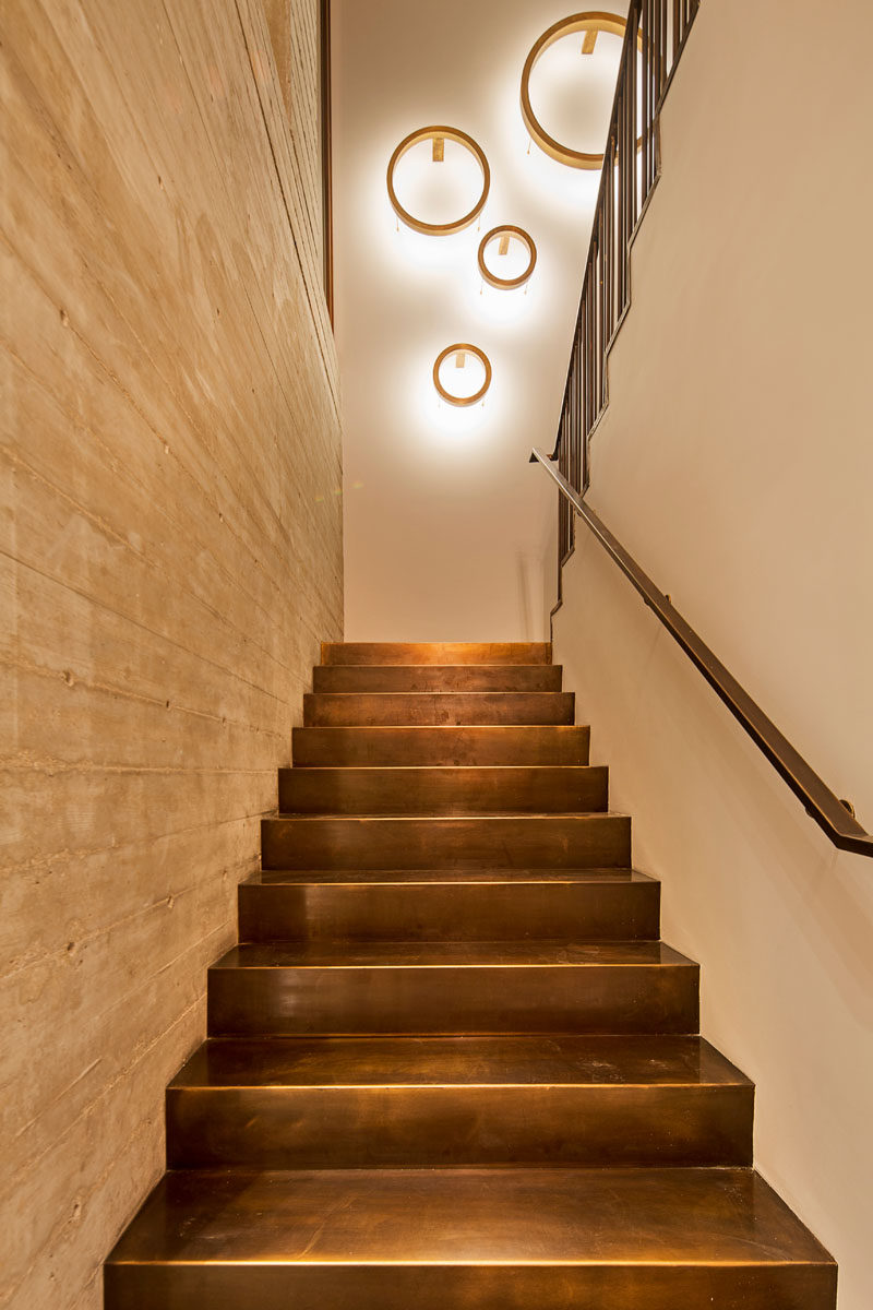 In this modern house, a staircase with bronze stairs and a concrete wall leads you up to the second floor of the home.