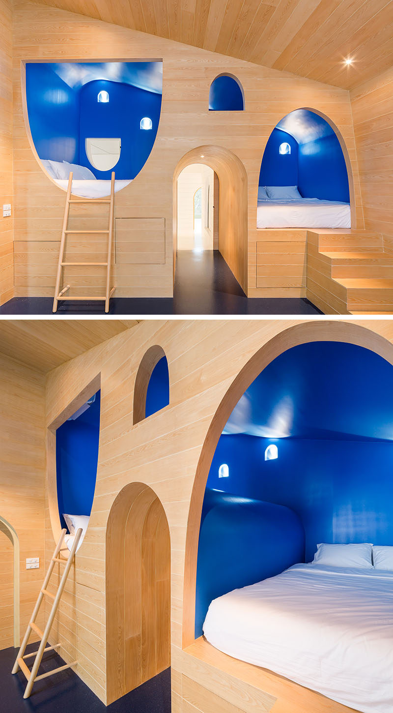 This whimsical yet modern boys bedroom features two built-in beds surrounded by royal blue walls that are built into the light wood wall.