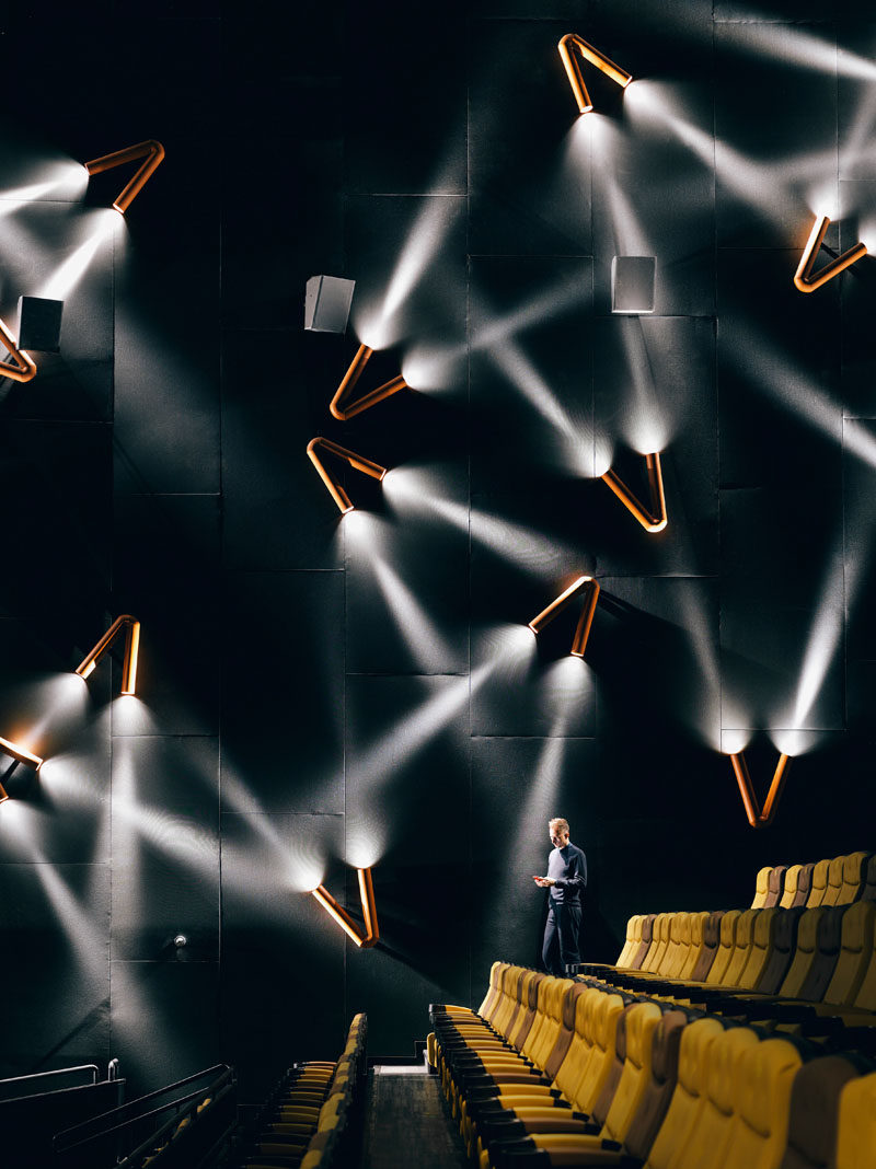 In this movie theater, metal pipes are bent into a V shape with lights at each end, to create a spotlight effect on the walls.