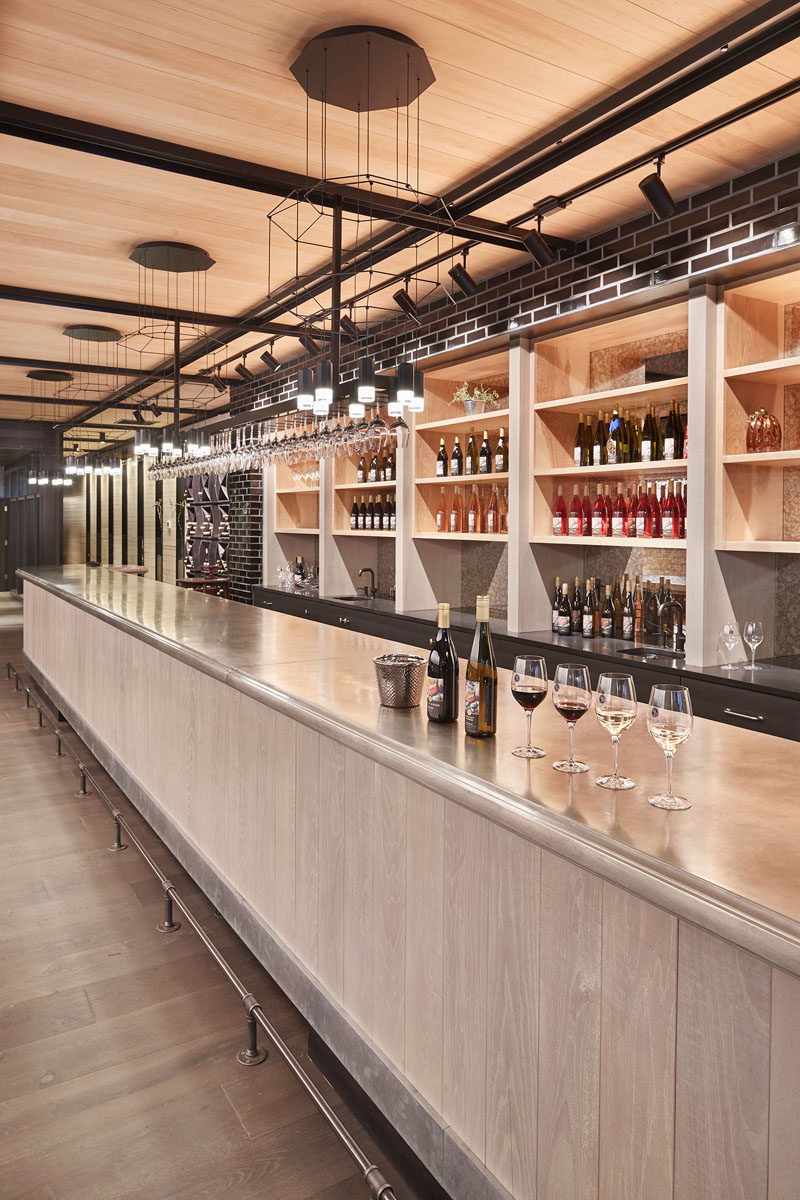 This contemporary wine tasting room has a custom made forty feet long (20m) pewter-topped, pine based bar is the focal point of the room. Black geometric light fixtures hang above the bar breaking up the neutral tones of the space.