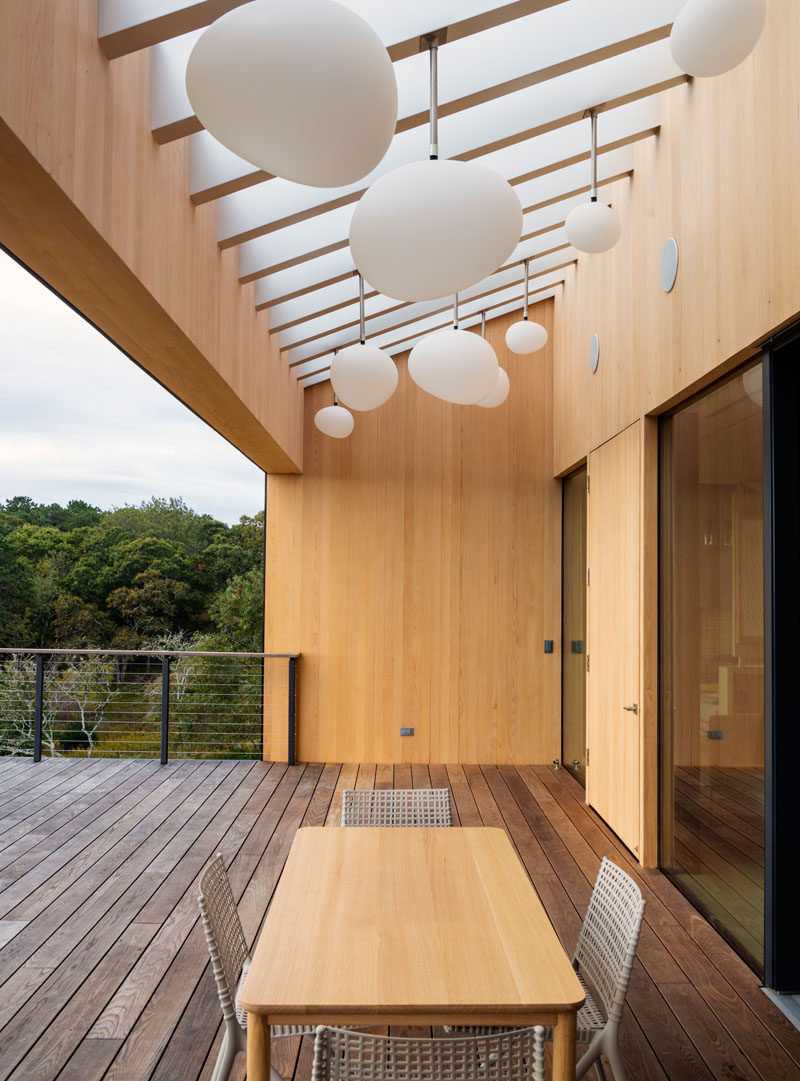 This outdoor dining area and deck has decorative pendant lights that look like an art installation during the day and create a fun atmosphere at night. A section of the deck above the table is covered to enable year-round outdoor entertaining.