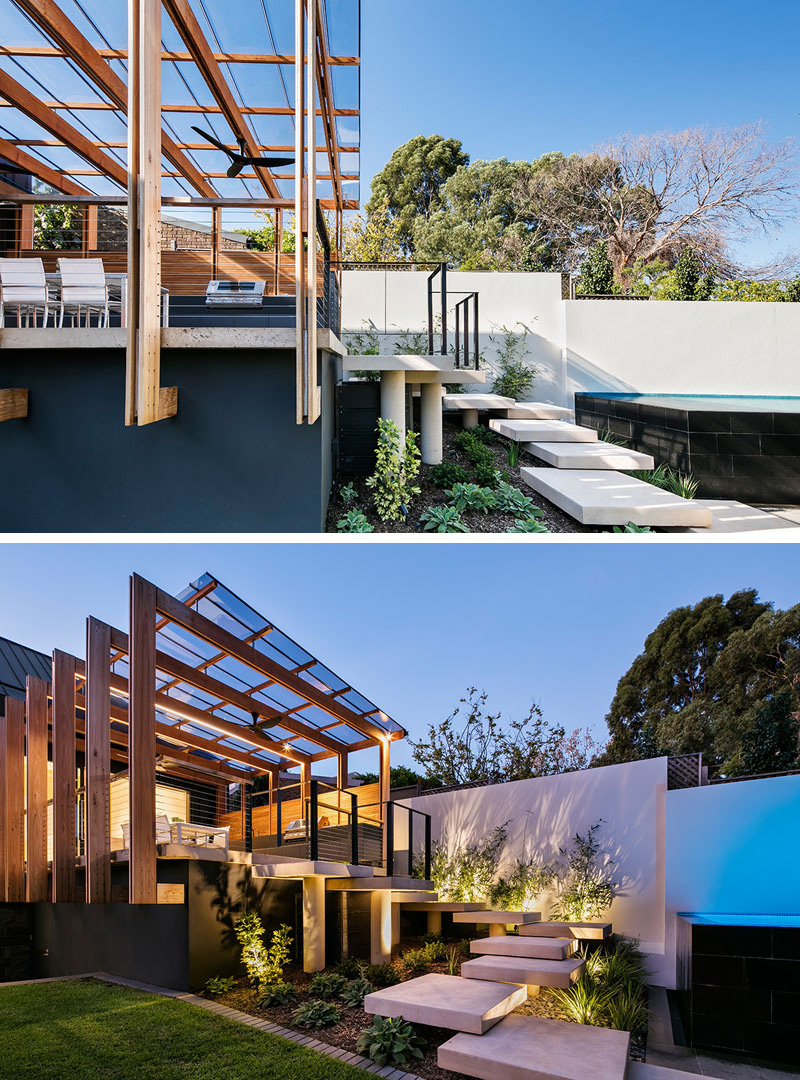 Oversized concrete steps take you from this modern entertaining deck with pergola down to the rest of the yard and lead to the above ground pool. Uplighting in the garden around the steps illuminates the path and makes it easy to see where you're going.