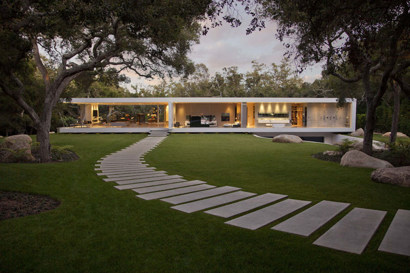 Staggered, rectangular concrete pavers create a curved modern path that runs through this contemporary backyard.