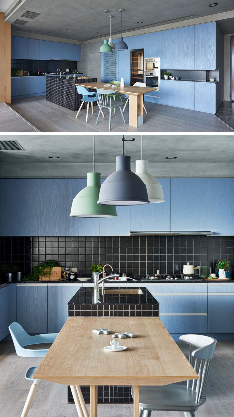 The lack of hardware combined with the grey wood floor and concrete ceiling really brighten and intensify the blue kitchen cabinets.