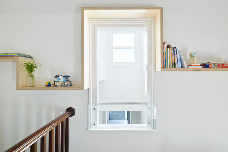 Simple and modern wood shelving has been added to the wall to perfectly frame this window and provide a place to store books and decorative objects.