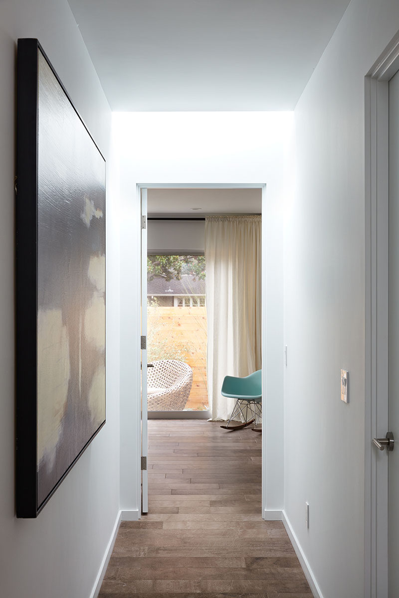 This white hallway has a skylight and leads to the bedrooms and bathrooms.