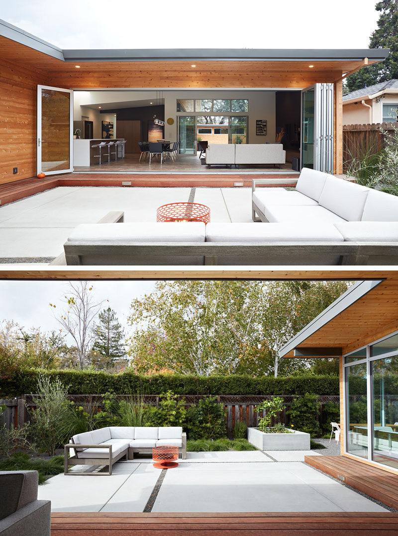 This modern house has a folding wall system that allows the interior of the home to open up to the outside courtyards, designed by landscaping company, Growsgreen. The patio has a comfortable outdoor corner sofa with white cushions that match the white walls of the interior of the home and a fire pit for cooler nights.