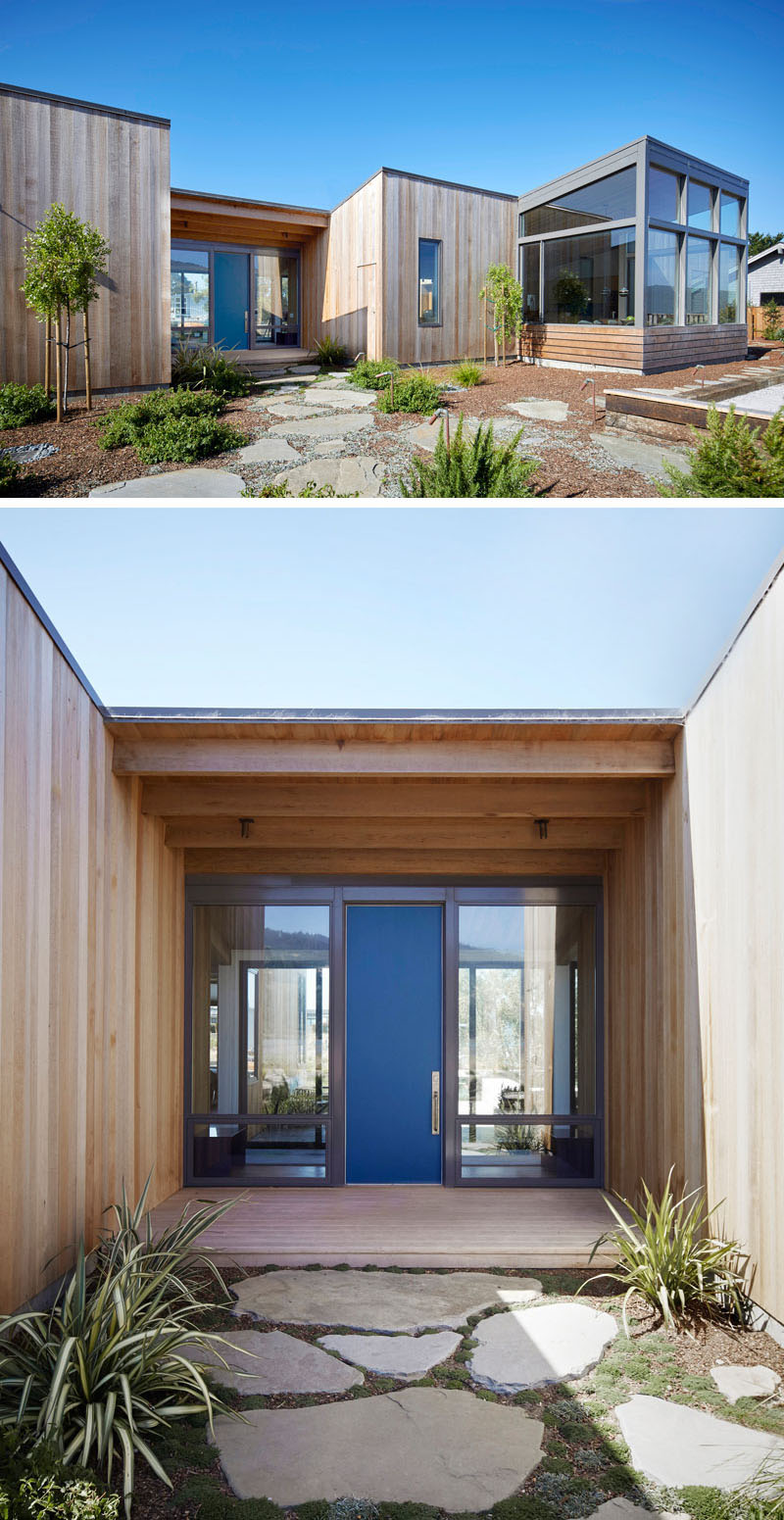 Surrounded by light wood cladding and large windows revealing the interior of the house, the front door provides a nice blue addition to the exterior of this modern home.