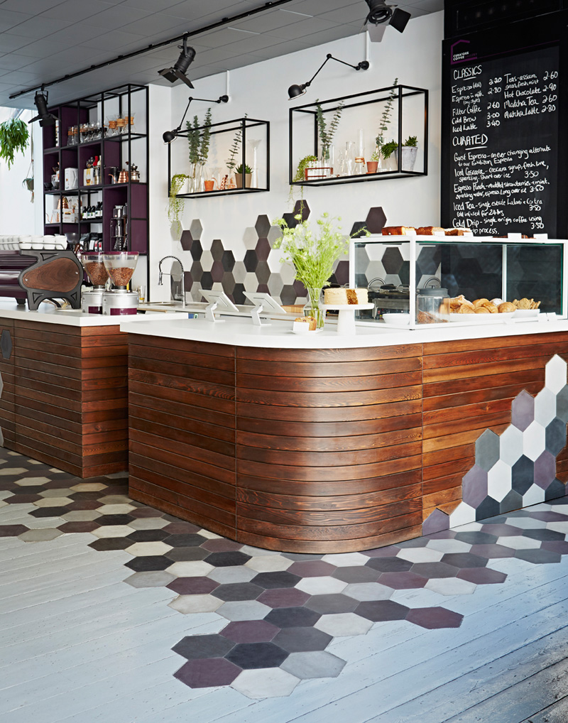 This coffee shop in London uses hexagons, wood, and a sophisticated yet playful color palette to create an inviting cafe.