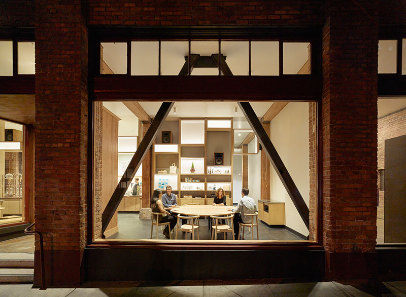  The large framed windows provide a glimpse of the minimally decorated interior of this modern cafe. Large wood seating arrangements allow for groups of people to stop by and work, or catch up with one another.