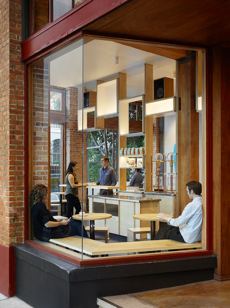 Banquet style, solid ash wood seating is utilised in the corner window of this modern cafe, providing extra space for patrons that allows them to look outside while others look in.