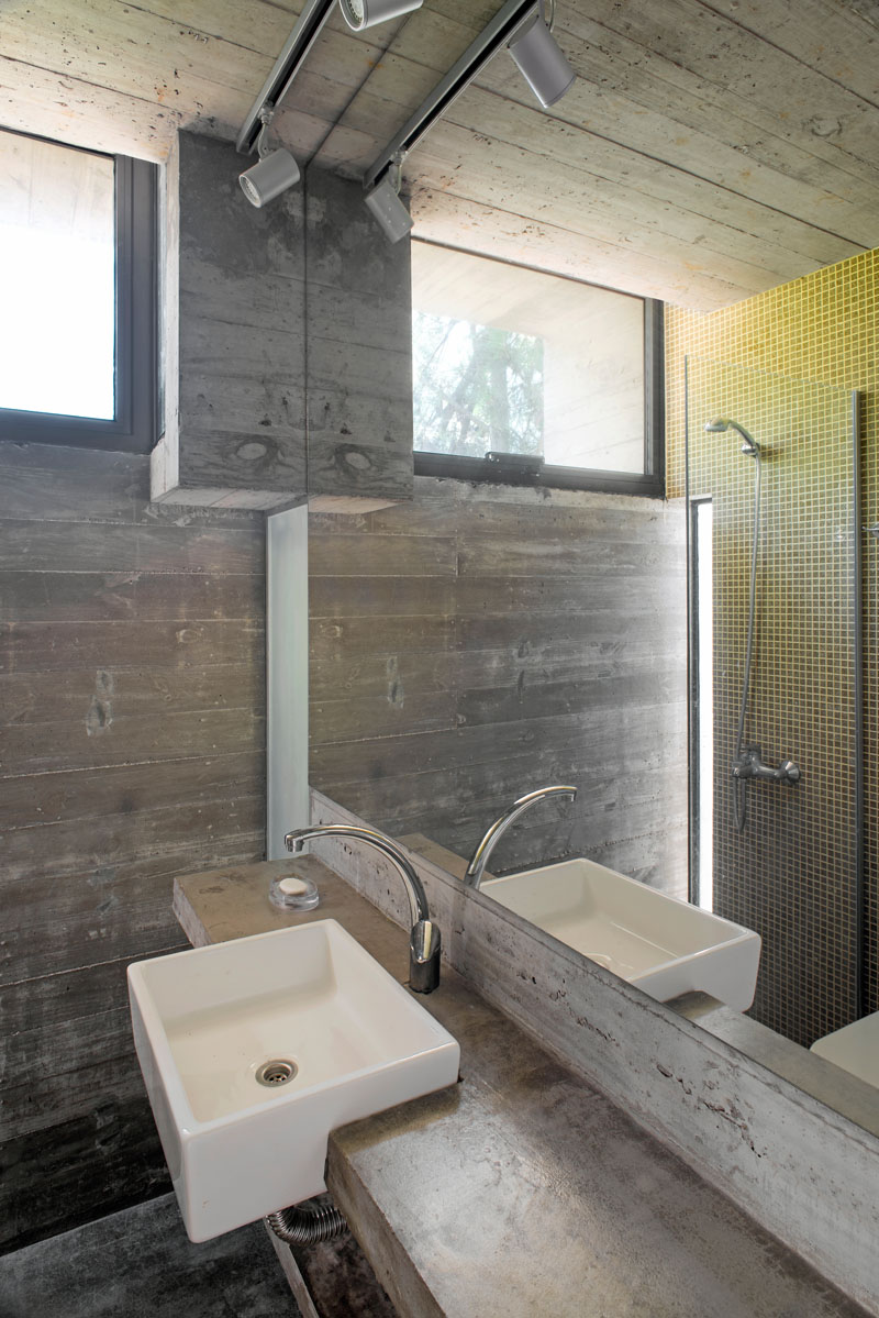 This modern bathroom has a glass surround shower with lime green tiles that stands opposite the rectangular white sink and large mirror.