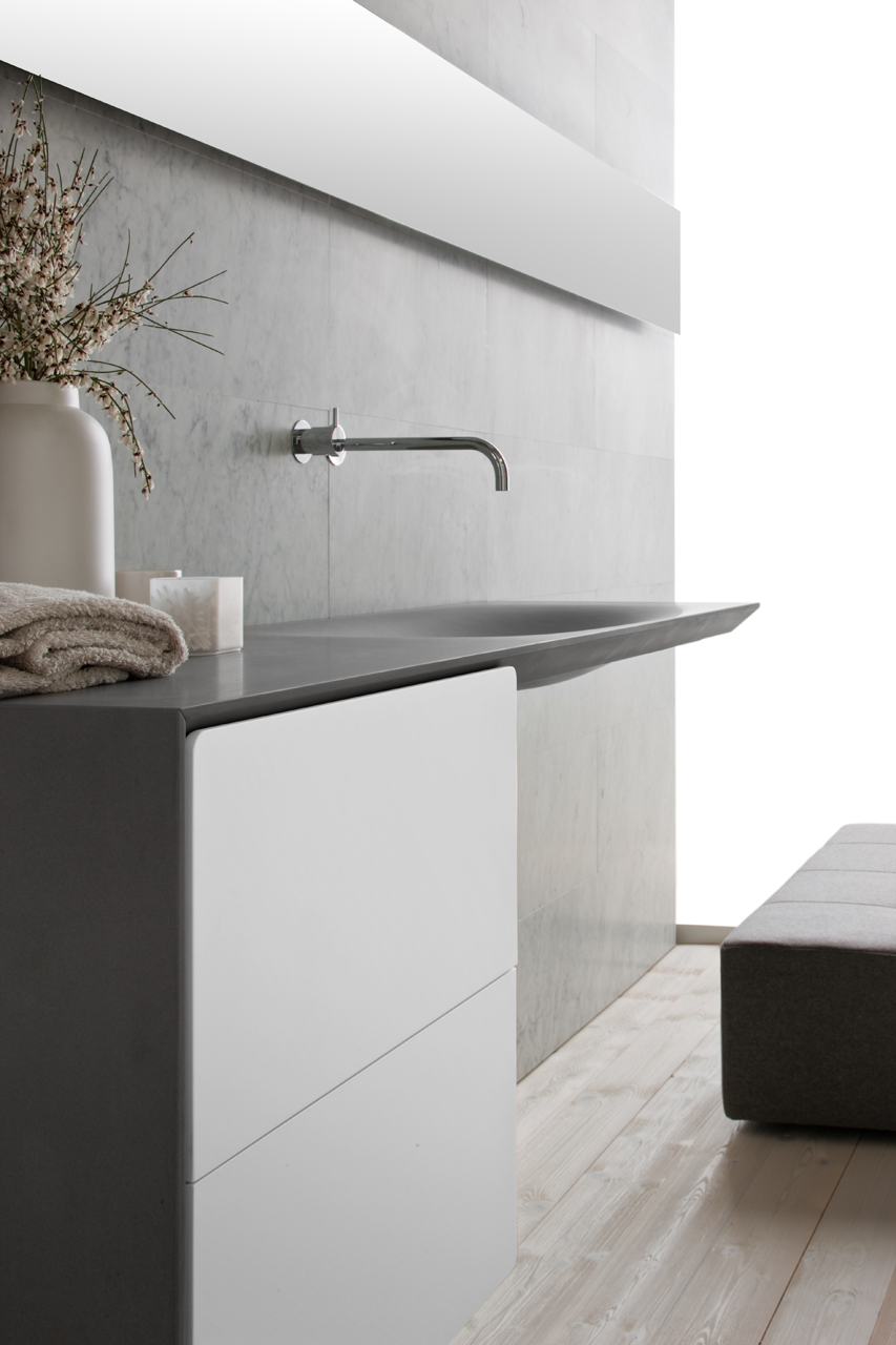 This modern grey stone sink is wall mounted, with large white drawers below to provide easy access to toiletries, and the slender chrome faucet is appealing to look at. 