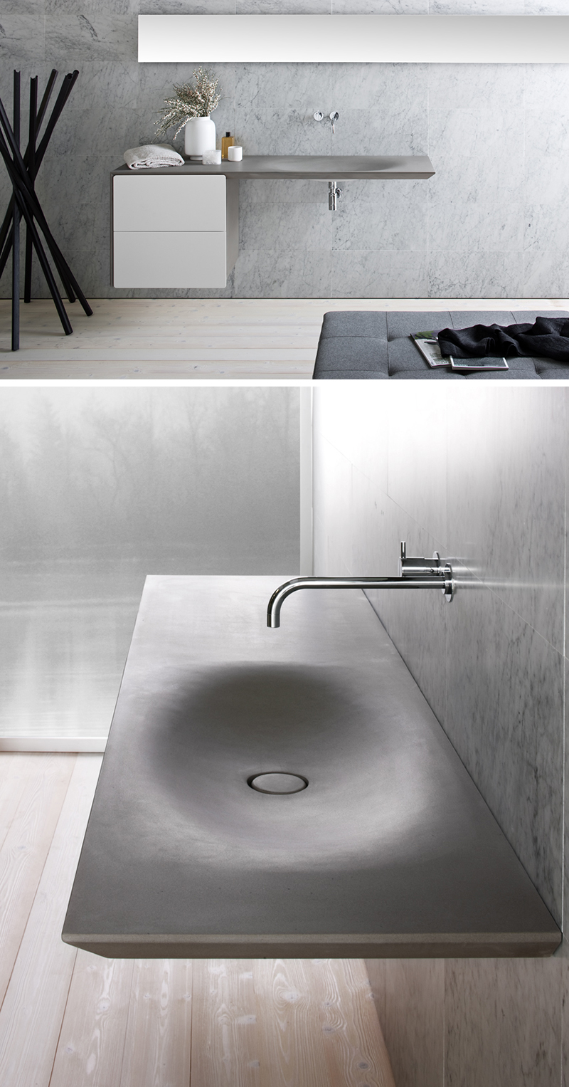 This modern, seamless grey stone sink is wall mounted with two white drawers and a chrome faucet. 