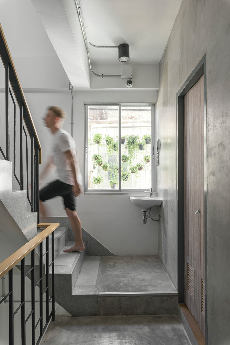 Concrete stairs with steel and wood railings lead you up to the sleeping areas of this modern hostel in Bangkok.