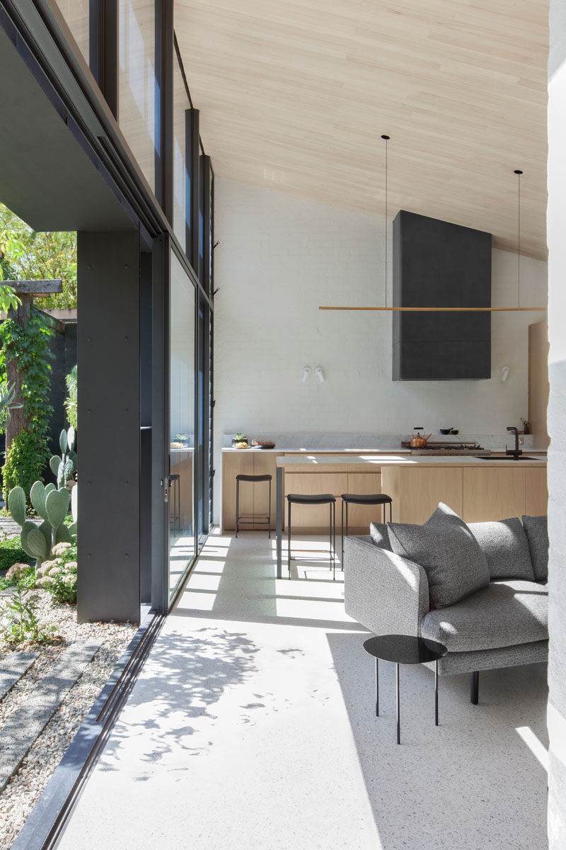 This modern house extension has large sliding glass doors that open to reveal the bright and airy interior with a slanted wood ceiling.