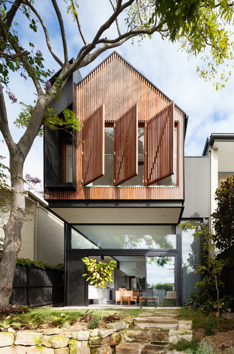 The rear extension on this modern house has an upper floor that cantilevers away from the house and provides shade for the small patio below.