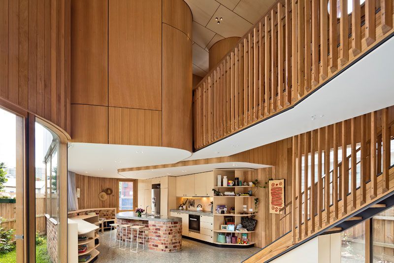 Inside this modern home, the curves continue with the walls and cabinetry. In the kitchen, the island is made from the same brick used on the exterior of the house, and curved open shelving creates additional storage without creating a hard and harsh edge.