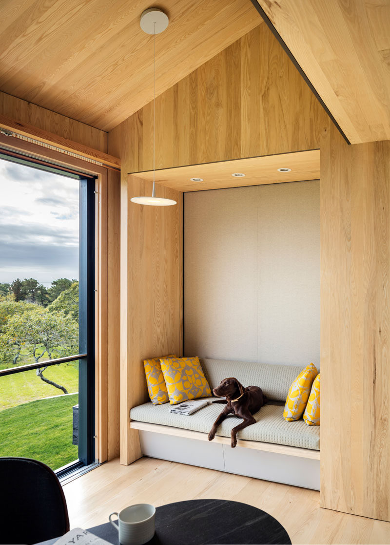 This built-in wood seating nook has a grey upholstery and yellow cushions for a pop of color.