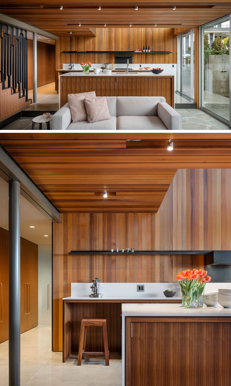 This modern kitchen is streamlined and efficient in its design, with the appliances paired down to the essentials. Instead of having upper kitchen cabinets, a minimalist black shelf lines the cedar wall, creating a contrast to the white countertops.