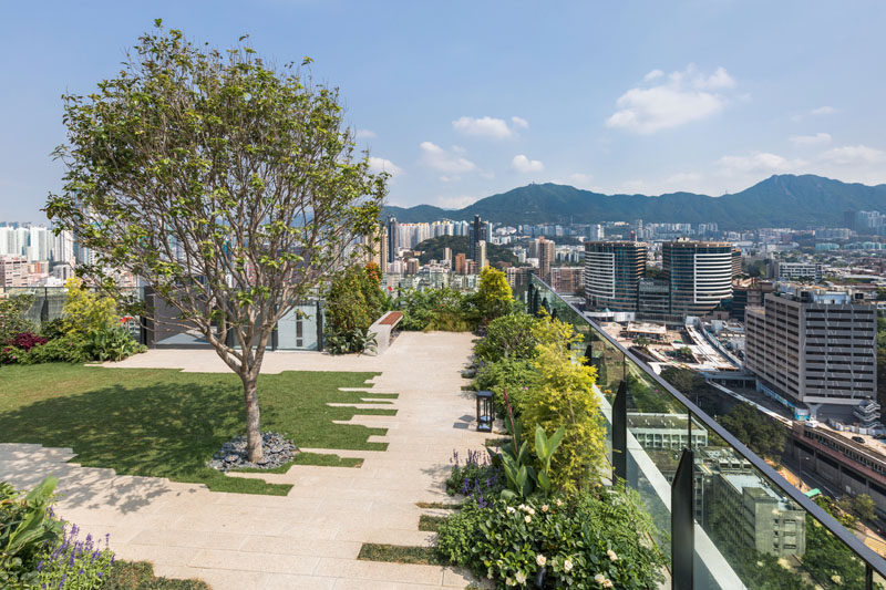 This modern residential building in Hong Kong has a rooftop park, complete with trees, a grassy area and benches.