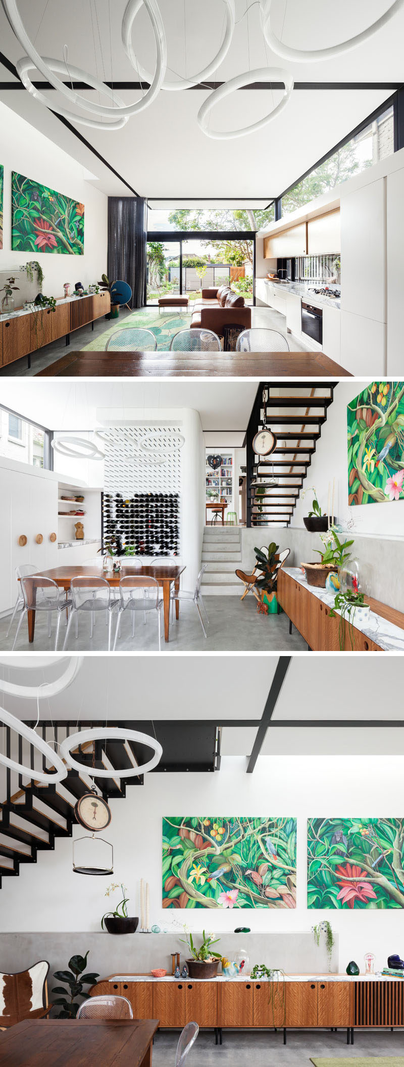 Inside this modern house, the living room, kitchen and dining room share the same space, with the light wood kitchen running alongside one wall. A wall of wine near the dining table and chairs doubles as a piece of art, while black beams break up the all white ceiling, and match the stairs at the end of the room.